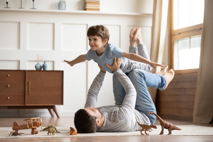 Dad holding child and playing in living room