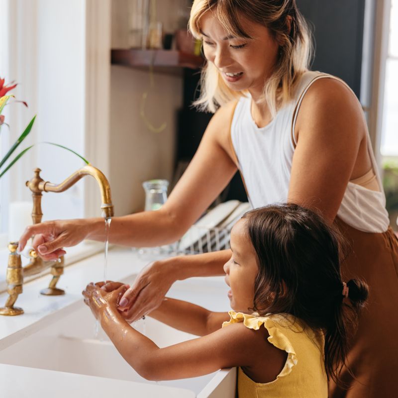 mother helping her daughter wash her hands
